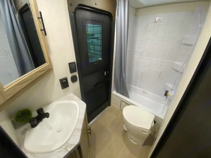 RV rental bathroom: A compact space with white sink, vanity, mirror, toilet, and bathtub/shower combo.. Grey Wolf 26DBH 2025