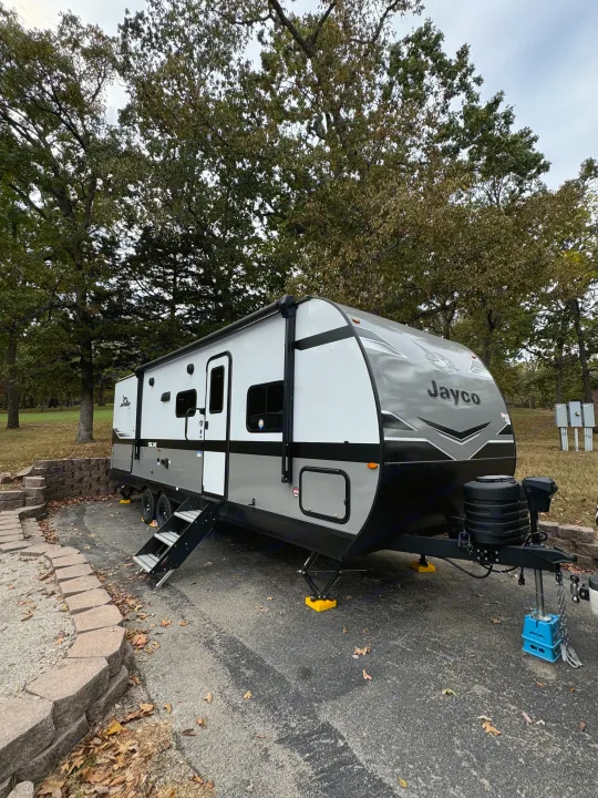 RV rental: Modern Jayco travel trailer parked at a treed campsite. Ready for your next outdoor adventure.. Jayco Jay Flight SLX 2024