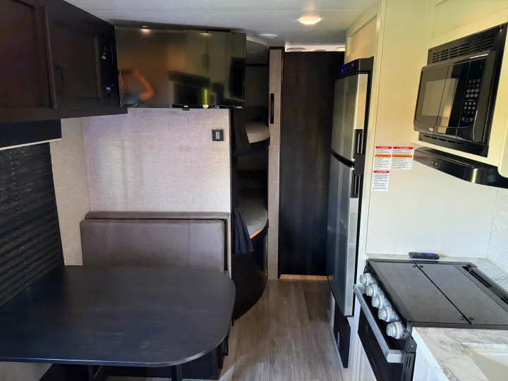 RV rental interior: dinette, kitchen with microwave, fridge, stove, and bunk beds.. Jayco Jay Flight SLX 2022