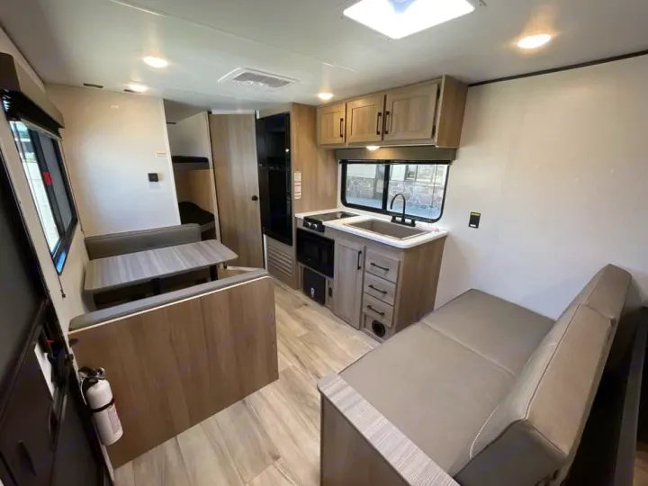 Explore this modern RV rental interior featuring a full kitchen, comfy dinette, and bunk beds for easy travel.. Coleman 23B Keystone 2025