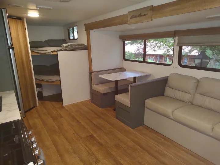 Inside an RV rental: view of the dinette, sofa, and bunk beds, offering a cozy and functional living space.. Heartland RVs Eddie Bauer 261BHC 2024