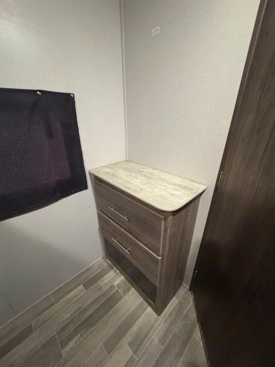 Compact RV rental interior featuring a wood dresser with drawers, light top, and wood-look floor. Efficient storage.. Crossroads RV Zinger 2020