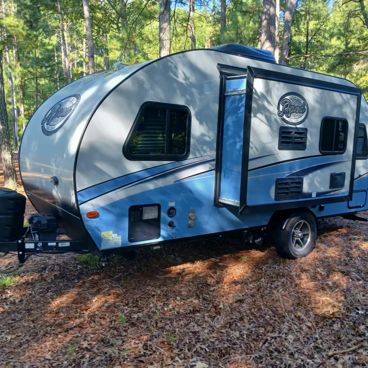 Light gray & blue R-Pod rv rental parked on fall leaves in a pine forest. Its door is open, inviting exploration.. R-Pod R-Pod Trailer 2018