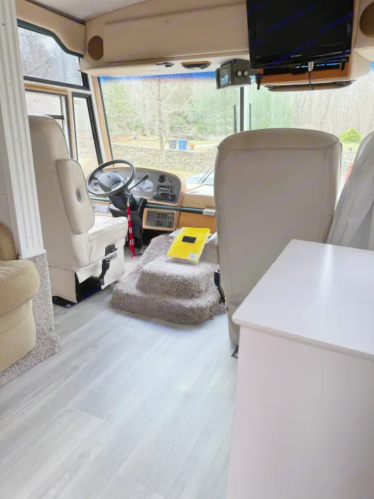Explore this RV rental's cockpit with light gray wood-look flooring, driver/passenger seats, dashboard, and overhead TV.. Fleetwood Southwind 36T 2000