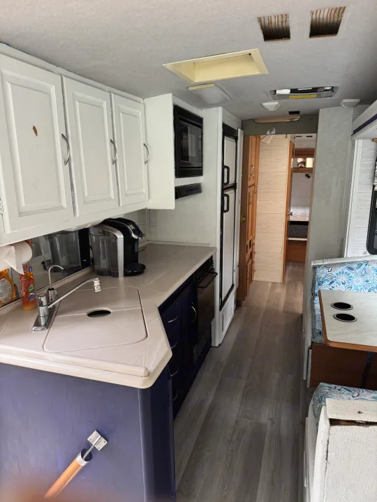 Renovated RV rental interior features a functional kitchen with sink, microwave, and dining nook. Modern flooring & bright cabinets.. Fleetwood Southwind 36T 2000
