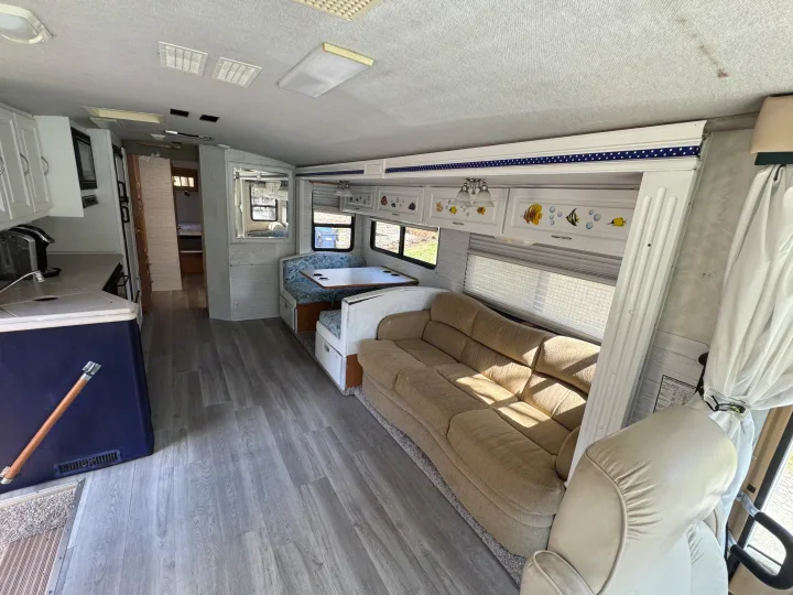 Spacious RV rental interior featuring a living area with a sofa, kitchen, and dinette, all on a modern grey laminate floor.. Fleetwood Southwind 36T 2000