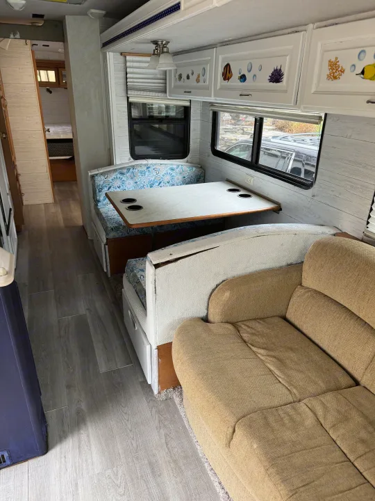 **RV rental** living space features new grey flooring, U-dinette with table, cozy sofa, and marine-themed cabinets.. Fleetwood Southwind 36T 2000