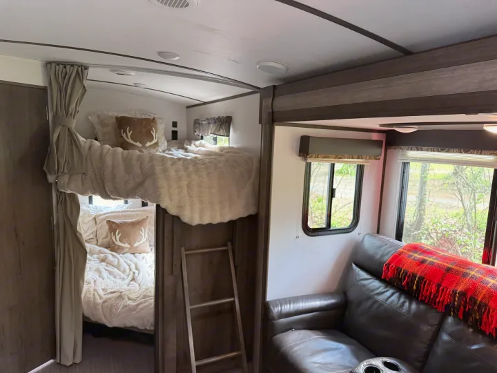 RV rental bunk area: two beds with cream bedding, antler pillows, ladder. Keystone RV Passport Grand Touring 2020