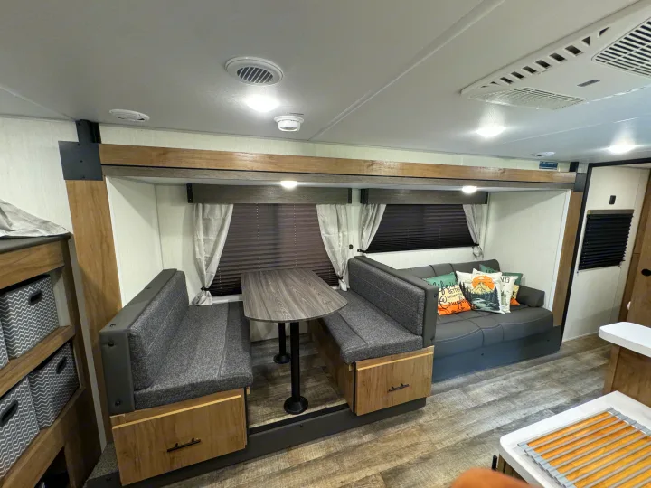 This inviting rv rental interior features a cozy dinette, comfortable sofa with throw pillows, and modern wood-look finishes.. Forest River Campsite reserve 26CJ 2025