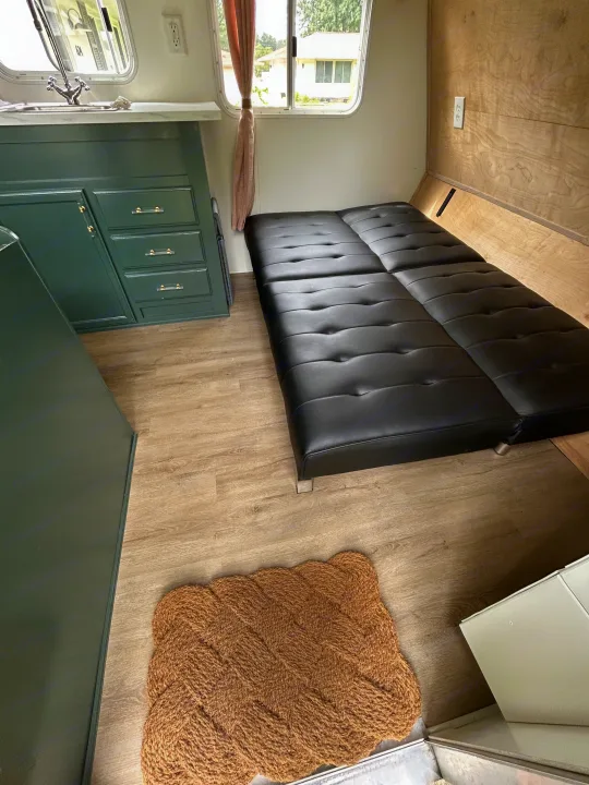 Cozy RV rental interior: green kitchen with sink, black sofa bed, wood-look floor, and window. Ideal camper living.. Jayco Jay Flight 2007
