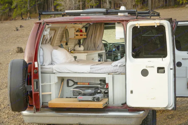 Inside this custom camper van, ideal for RV rental, a bed, kitchen, and pull-out stove are visible.. Ford Econoline 2006