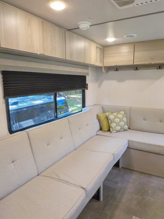 Modern RV rental living space with light wood cabinets, plush L-shaped sofa, window, and bright ceiling lights.. Forest River Salem FSX 266BHLE 2025