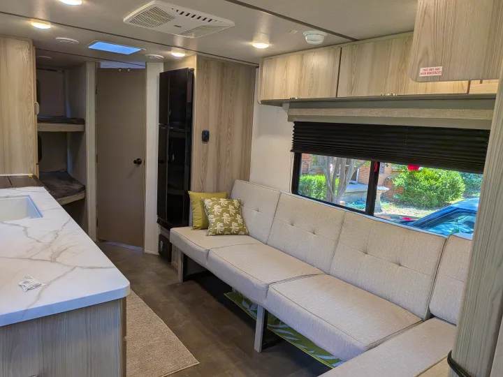 Step inside this RV rental: a bright interior with a sofa, kitchen, bunk beds, and overhead storage.. Forest River Salem FSX 266BHLE 2025