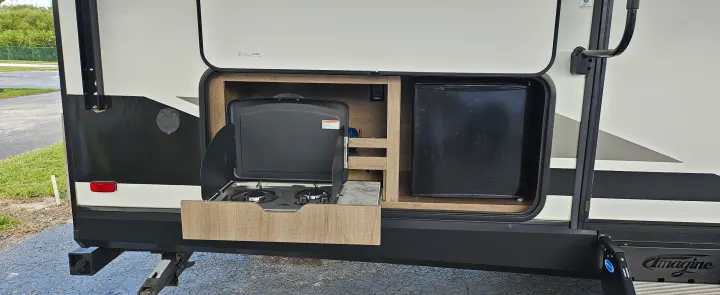 RV rental outdoor kitchen with slide-out stove and mini-fridge for convenient camping meals and outdoor cooking.. Grand Design Imagine 2021