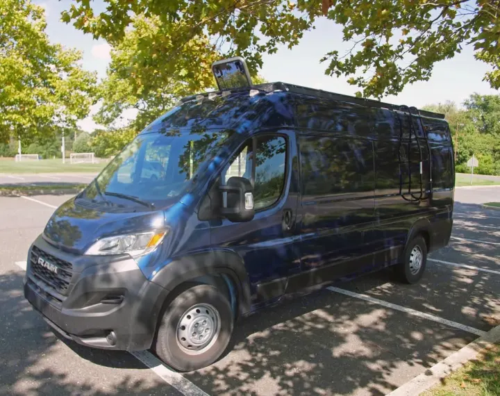 A dark blue Ram ProMaster rv rental camper van, converted for travel, parked under shady trees.. Dodge Ram Promaster 3500 2023