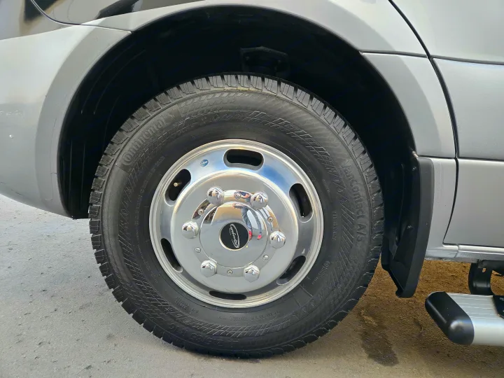A Continental VanContact A/S tire and chrome Renegade wheel on an RV rental. Details include tire tread and vehicle body.. Renegade Custom Coaches Vienna 2021