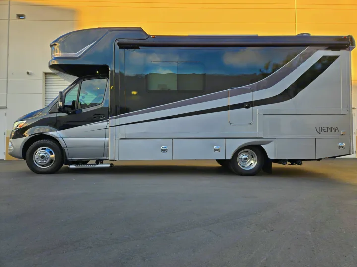 This modern black & silver Class C RV rental is a luxurious motorhome, ready for adventure. Parked on asphalt.. Renegade Custom Coaches Vienna 2021