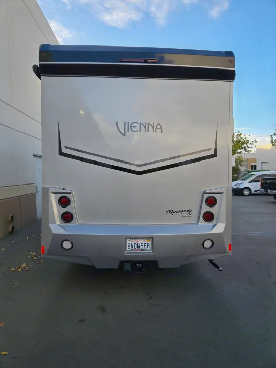 Rear view of a sleek, silver Vienna Renegade motorhome, featuring its license plate (8V0W588) and tow hitch, ideal for rv rental.. Renegade Custom Coaches Vienna 2021