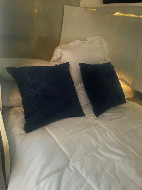 Comfortable RV rental sleeping area featuring crisp white bedding and two decorative blue patterned pillows.. Airstream Bambi 2020