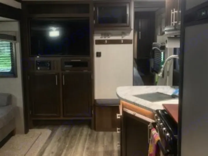 Explore this RV rental's inviting interior: A comfy living area with TV on the left, modern kitchen with sink on the right. Dark wood decor.. Jayco Jay Flight 2019