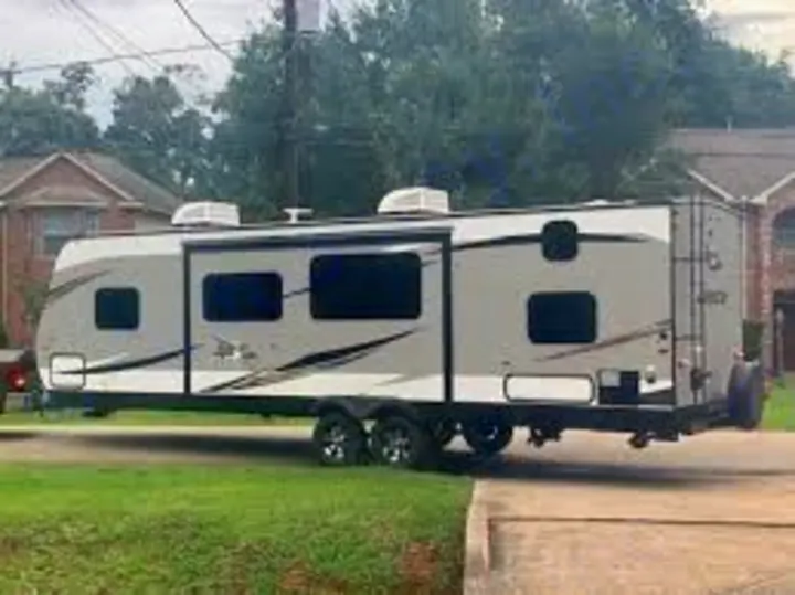 A modern gray and white RV/travel trailer, featuring slide-outs, parked roadside. Ideal for your next RV rental road trip.. Jayco Jay Flight 2019