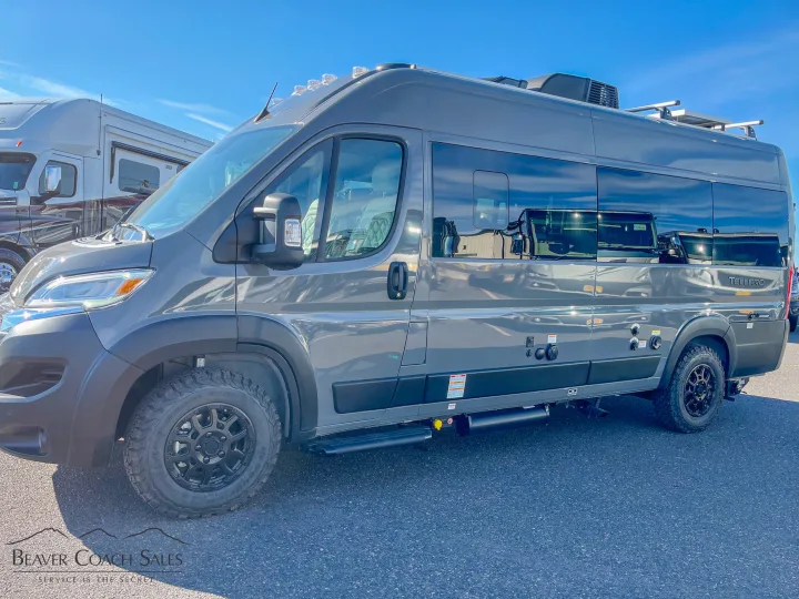 This gray Thor Tellaro Class B camper van, ideal for rv rental, is parked outdoors. Notice its off-road tires and roof rack.. Thor Tellaro 2026