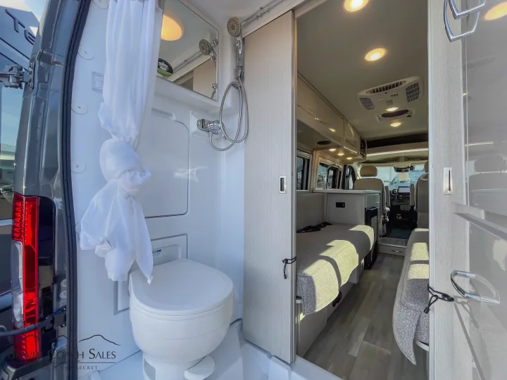 Compact RV rental interior: integrated bathroom with toilet, shower, and convertible sleeping area.. Thor Tellaro 2026
