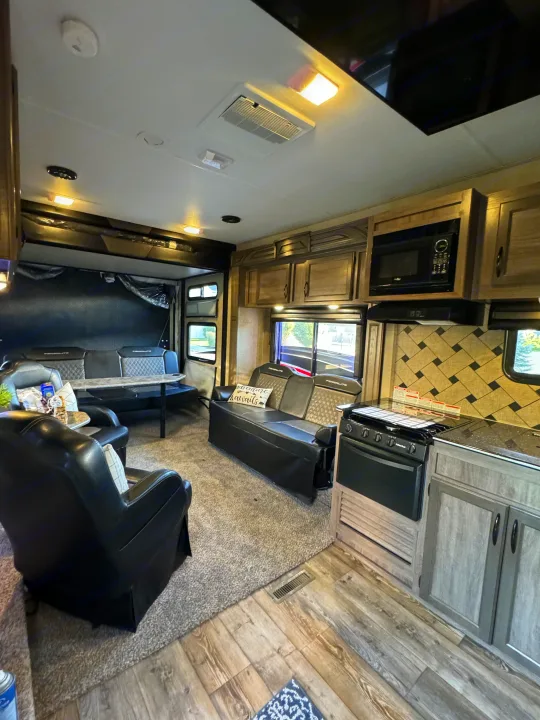 RV rental interior: Modern living space with comfy seating, kitchen, and mixed wood/carpet flooring. Great for trips.. Pacific Coachworks Powerlite 2017