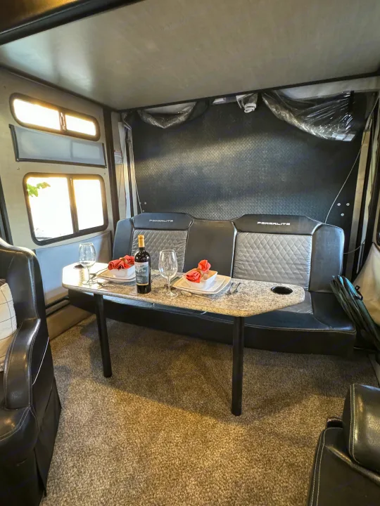 Inside an RV rental: a welcoming dining and living space with a set table, wine, and comfy seating.. Pacific Coachworks Powerlite 2017
