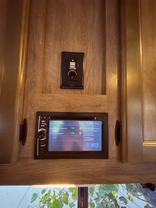 RV rental wall with USB/12V charging ports & a car stereo showing Bluetooth connections like 'Allan's iPhone'.. Pacific Coachworks Powerlite 2017