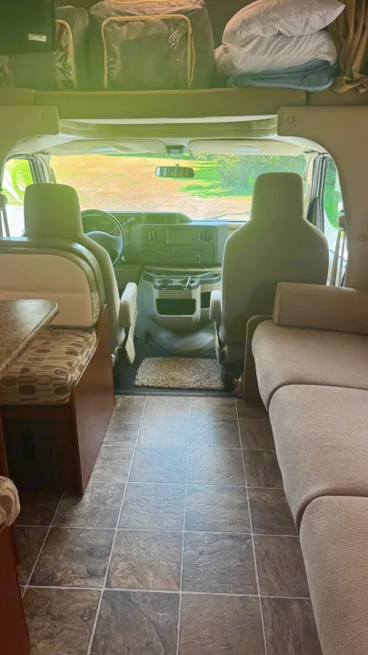 RV rental: Inside view of a cozy mobile living space, with cockpit, sofa, and overhead bunk.. Thor Chateau 2012