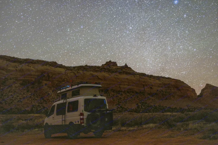 RV rental camper van parked under a dazzling, star-filled night sky in a vast desert landscape.. Sportsmobile Regular Body 4X4 2017