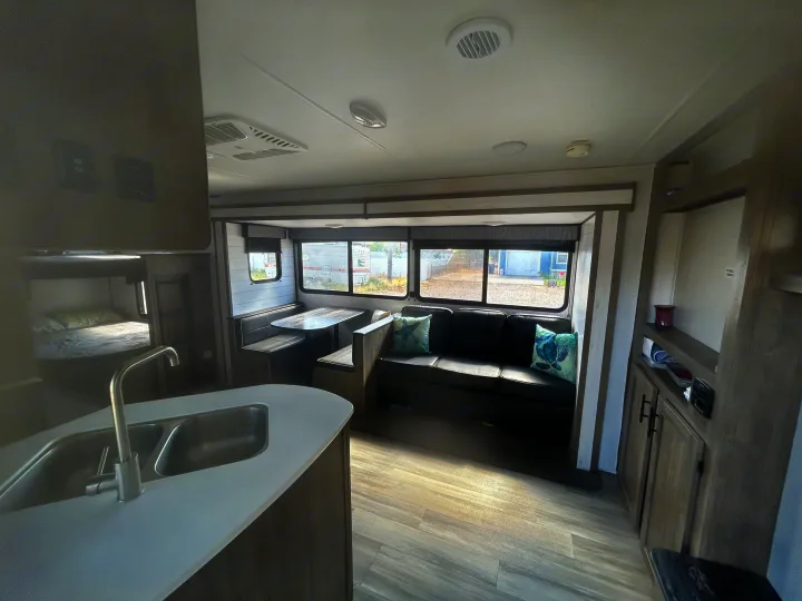 Spacious RV rental interior featuring a modern kitchen, dining booth, living sofa, and bunk beds, ideal for family travel.. Heartland RVs Pioneer 2022