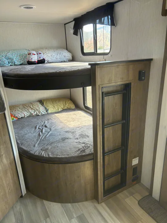 Cozy RV rental interior featuring comfortable bunk beds with ladder access, perfect for family travel.. Heartland RVs Pioneer 2022