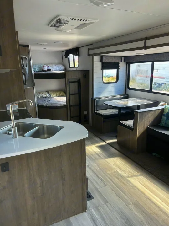Modern RV rental interior: kitchen, bunk beds, and dinette visible. Bright, spacious home on wheels for travel.. Heartland RVs Pioneer 2022