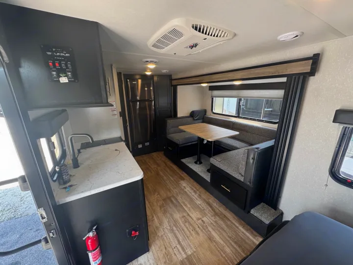 View of a well-equipped RV rental interior, showing a dinette, kitchenette, refrigerator, and AC unit.. Forest River Cherokee Wolf Pup 2021
