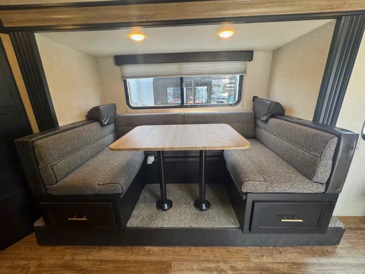 This RV rental interior features a cozy U-shaped dinette with a table and window, perfect for dining and travel.. Forest River Cherokee Wolf Pup 2021