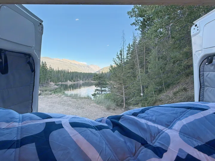 Cozy RV rental bed with serene lake & mountain view. Perfect for peaceful van life camping adventures.. Mercedes-Benz Sprinter 2024