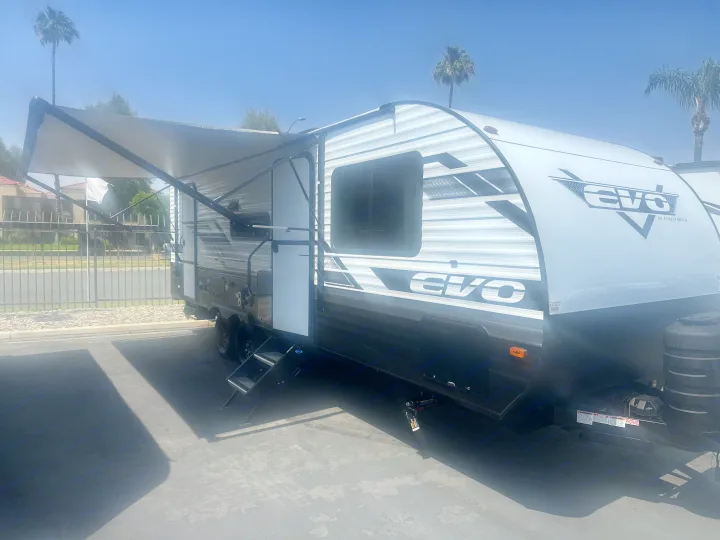 Modern white & grey EVO travel trailer RV with extended awning and steps, perfect for your next rv rental getaway.. Forest River Evo 2400bhl 2024