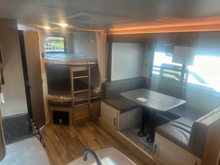Inside an RV rental, showcasing bunk beds, a cozy dinette, and a glimpse of the kitchen. Ideal for family getaways.. Forest River Evo 2400bhl 2024