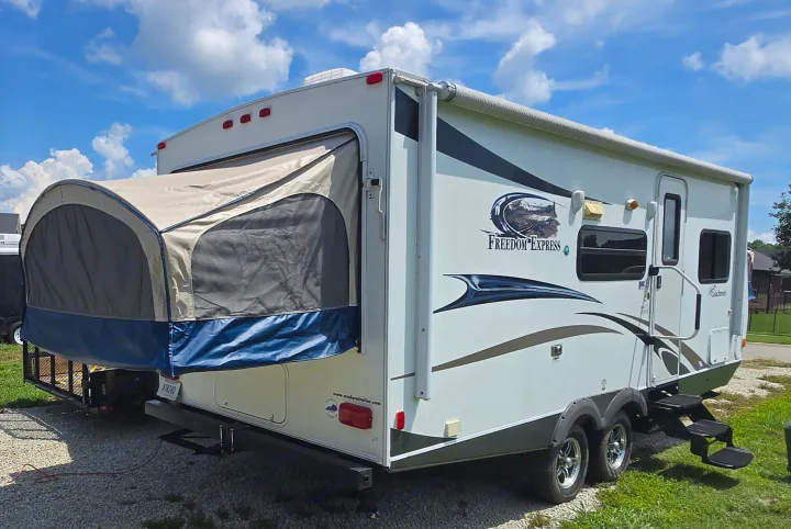 This white hybrid RV rental, a Coachmen Freedom Express travel trailer, features an expanded canvas bed end.. Coachmen Freedom express ltz 2014