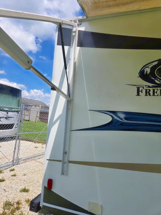 A recreational vehicle (RV) rental side view with its white awning partially extended, perfect for sunny outdoor travel.. Coachmen Freedom express ltz 2014