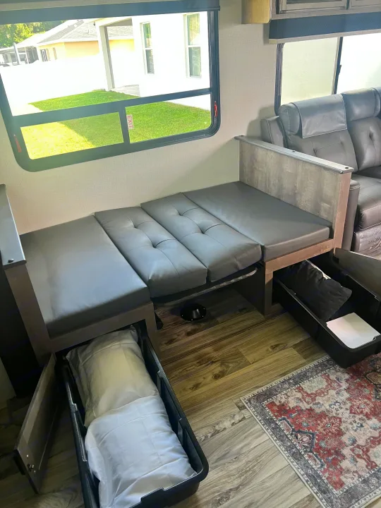 RV rental interior: convertible dinette seating, under-seat storage for bedding, and wood-look flooring with a table base.. SportTrek Venture 2024