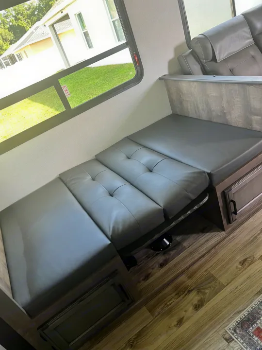 RV rental interior featuring a gray convertible dinette bed, plush recliners, and a bright window view of outdoors.. SportTrek Venture 2024