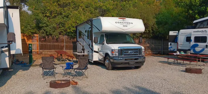 This Coachmen Freelander RV rental is ready for camping at a gravel site, complete with picnic table, chairs, and fire pit.. Freelander 21QSS 2025