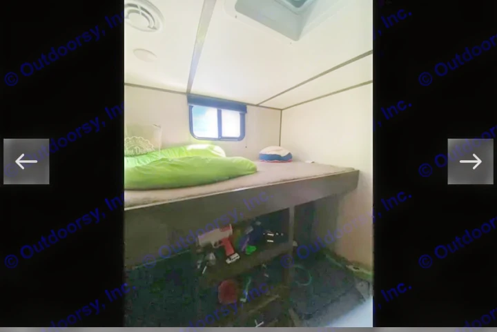 Inside this RV rental: a cozy bunk bed setup with a green sleeping bag, window, and under-bed storage, ideal for families.. Coachmen Lantern 2021