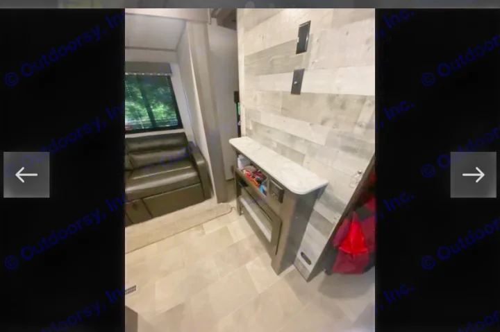 RV rental interior showing a black reclining sofa, electric fireplace, and modern wood-paneled walls.. Coachmen Lantern 2021
