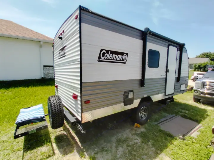 A Coleman travel trailer, a great option for an rv rental, parked on grass. White and gray, ready for adventures.. Dutchmen 17B 2024