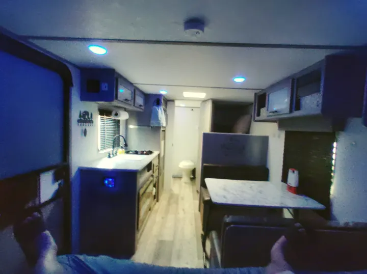 Relaxing RV rental interior: kitchen, dining, and bedroom areas visible, softly lit by blue LEDs.. Dutchmen 17B 2024