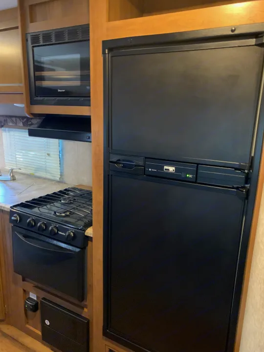 This RV rental kitchen features a black Norcold refrigerator, Magic Chef microwave, and Suburban stove with oven.. Coachmen Other 2018